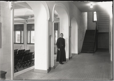Reproduction d’une photographie du p&egrave;re Ren&eacute; Lamoureux o.m.i., dans le corridor de l’entr&eacute;e du nouvel &eacute;difice de l’&Eacute;cole normale de l’Universit&eacute; d’Ottawa, Ottawa (Ontario), 1931.