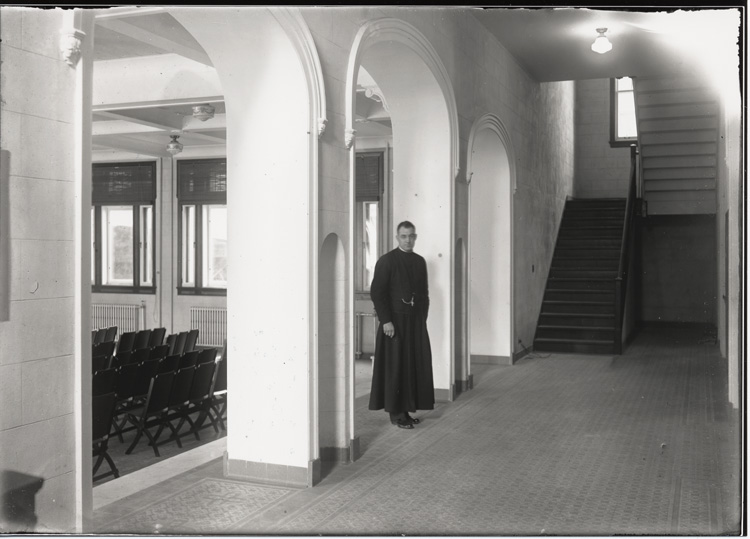 Reproduction d’une photographie du p&egrave;re Ren&eacute; Lamoureux o.m.i., dans le corridor de l’entr&eacute;e du nouvel &eacute;difice de l’&Eacute;cole normale de l’Universit&eacute; d’Ottawa, Ottawa (Ontario), 1931.