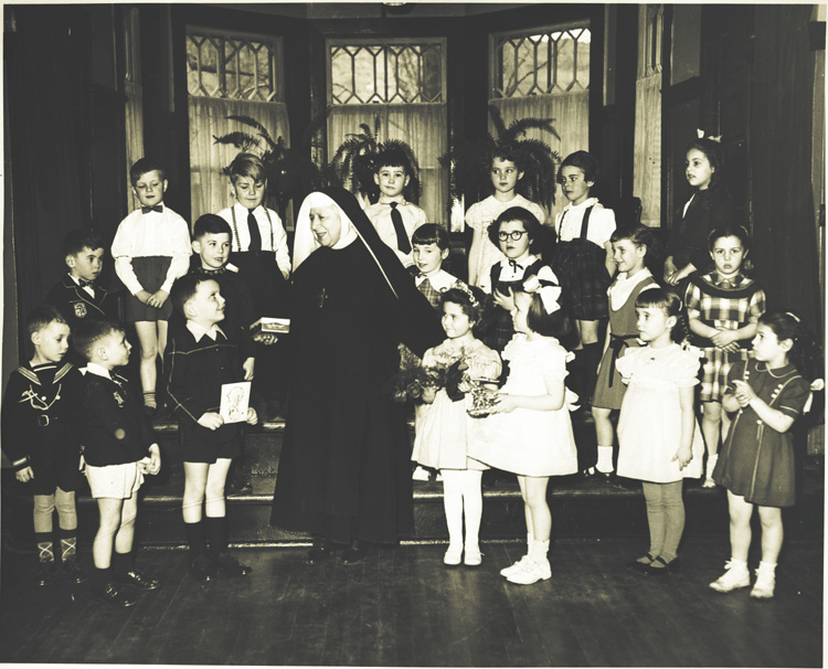 Reproduction d’une photographie des enfants de la maternelle du 360 rue Kenwood, Ottawa (Ontario), avec leur enseignante, soeur Saint-Thomas d’Aquin, ca 1960.