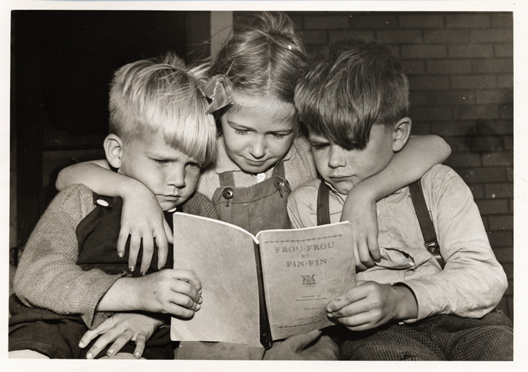 Reproduction d’une photographie de Billy, Rachel et Denny, enfants de M. et Mme William Allen, lisant le manuel d’initiation &agrave; la lecture Frou-Frou et Fin-Fin de Robert Gauthier, septembre 1946.