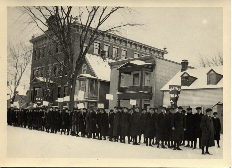 Reproduction d’une photographie d’une manifestation d’&eacute;coliers contre le R&egrave;glement XVII, devant l’&eacute;cole Br&eacute;beuf, square Anglesea dans la basse-ville d’Ottawa (Ontario), &agrave; la fin janvier ou au d&eacute;but f&eacute;vrier 1916.