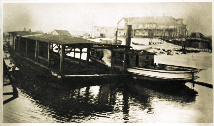 Reproduction d’une photographie de bateaux ancr&eacute;es devant la Blind River Hotel sur la rue Hudson &agrave; Blind River (Ontario), ca 1910.