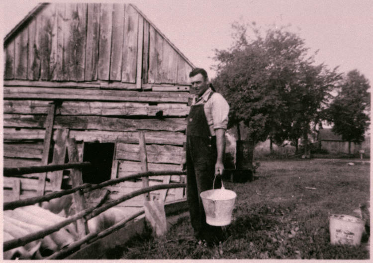 Reproduction d’une photographie de G&eacute;rard Gratton s’appr&ecirc;tant &agrave; nourrir les cochons, Wendover (Ontario), 1945.