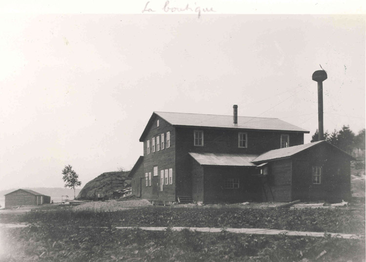 Reproduction du recto d’une carte postale illustrant la boutique et la scierie situ&eacute;es pr&egrave;s du village de Spanich River (Ontario), 1917.