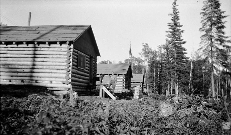 Reproduction d’une photographie d’une s&eacute;rie de camps de bois rond de la mine Shenango (mine d’or), Oba (Ontario), 1er ao&ucirc;t 1936.